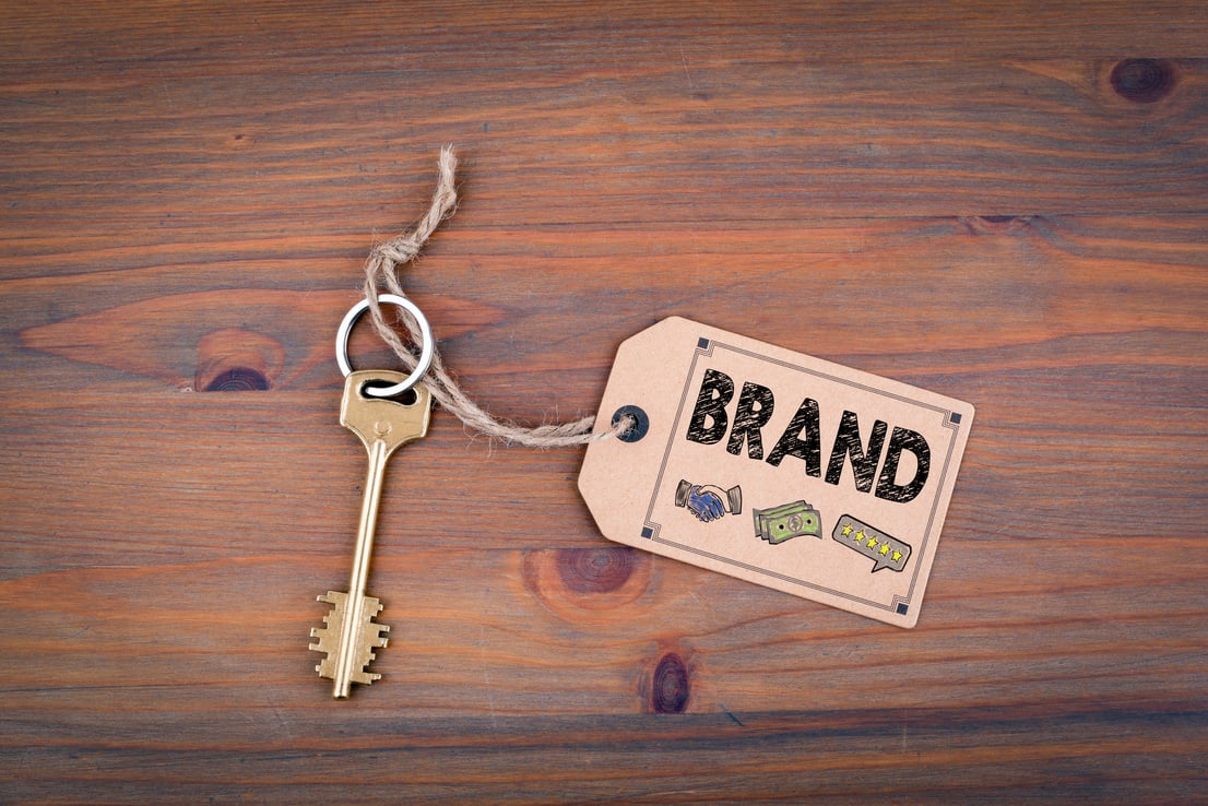 Brand concept. Brass key with a price tag on a wooden table